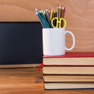 Close-up of books stack with colored pencil on a mug